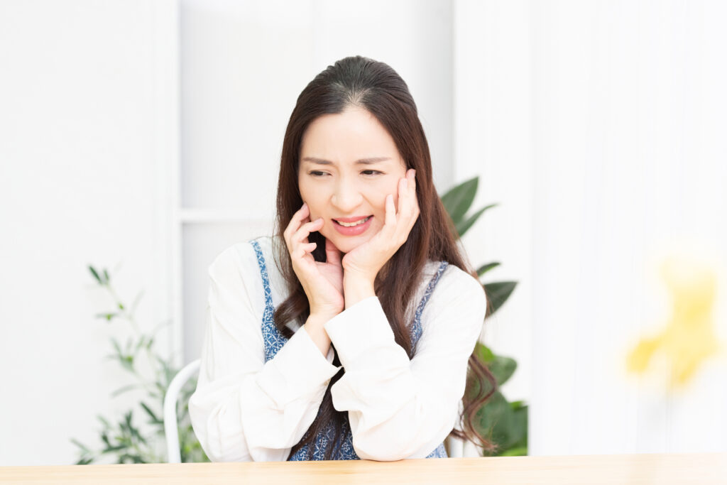 リビングで座りながら歯が痛くて頬に手を当て