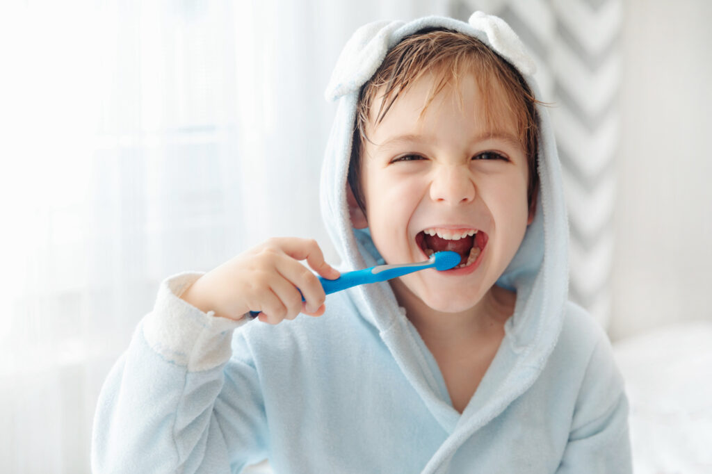 Morning routine, smiling happy child brushing teeth with toothbrush. Dental hygiene of little boy, medical care.